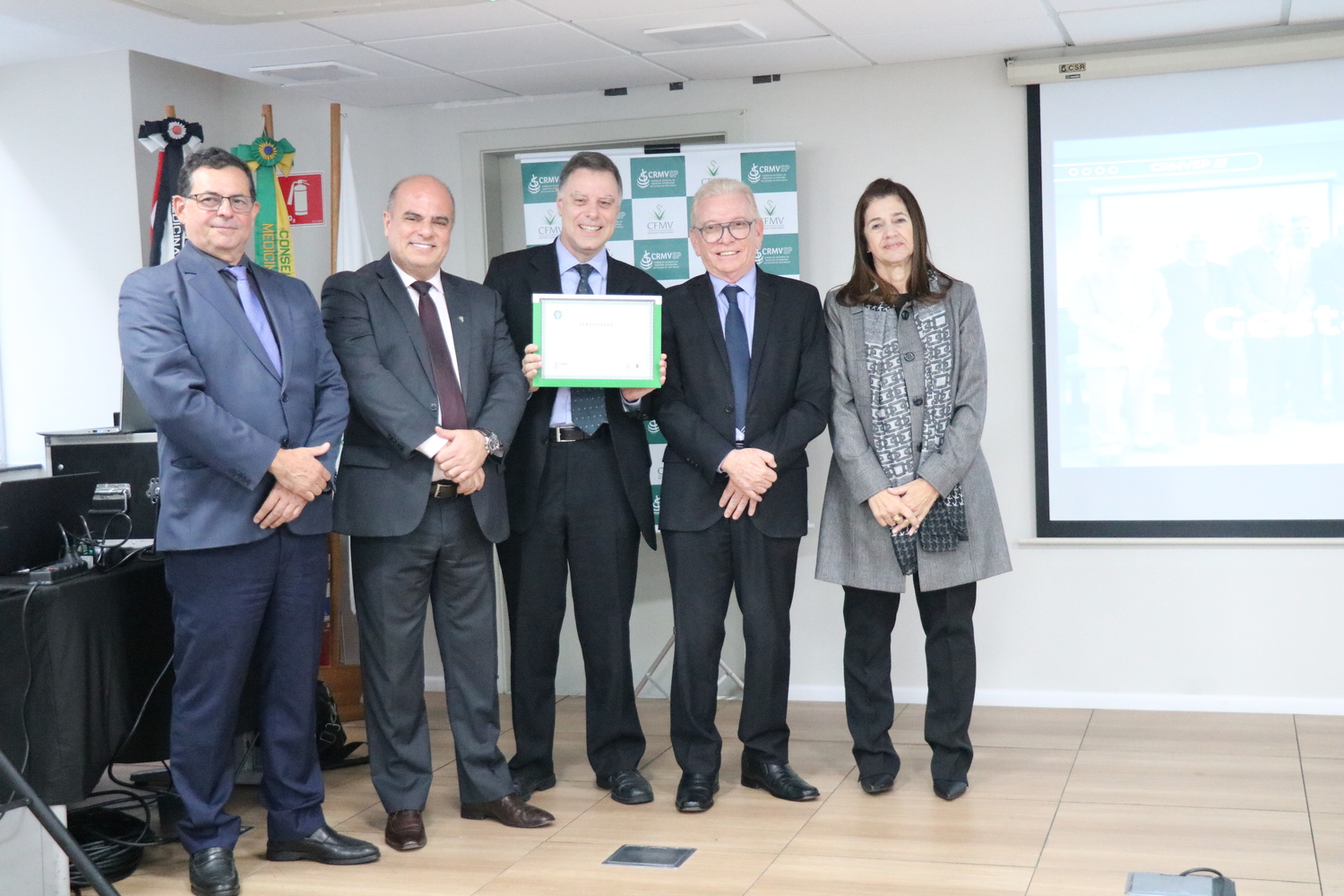 No palco, os membros da Diretoria Executiva do CRMV-SP posam ao lado de conselheiro da autarquia homenageado pelo trabalho desempenhado em suas funções.