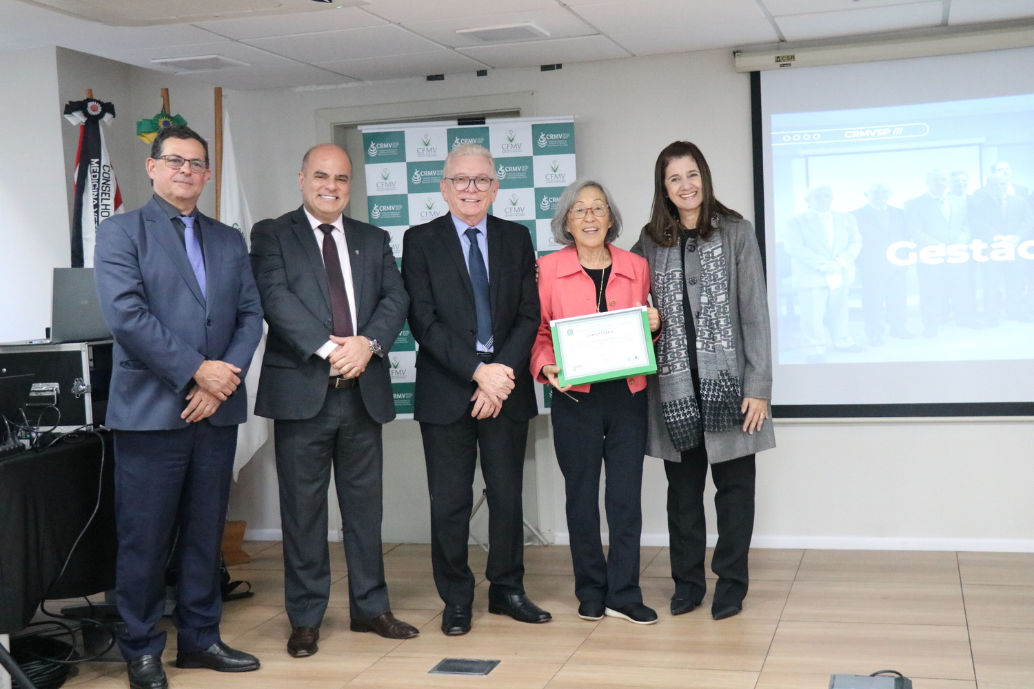 No palco, os membros da Diretoria Executiva do CRMV-SP posam ao lado de ex-conselheira da autarquia homenageada pelo trabalho desempenhado em suas funções.