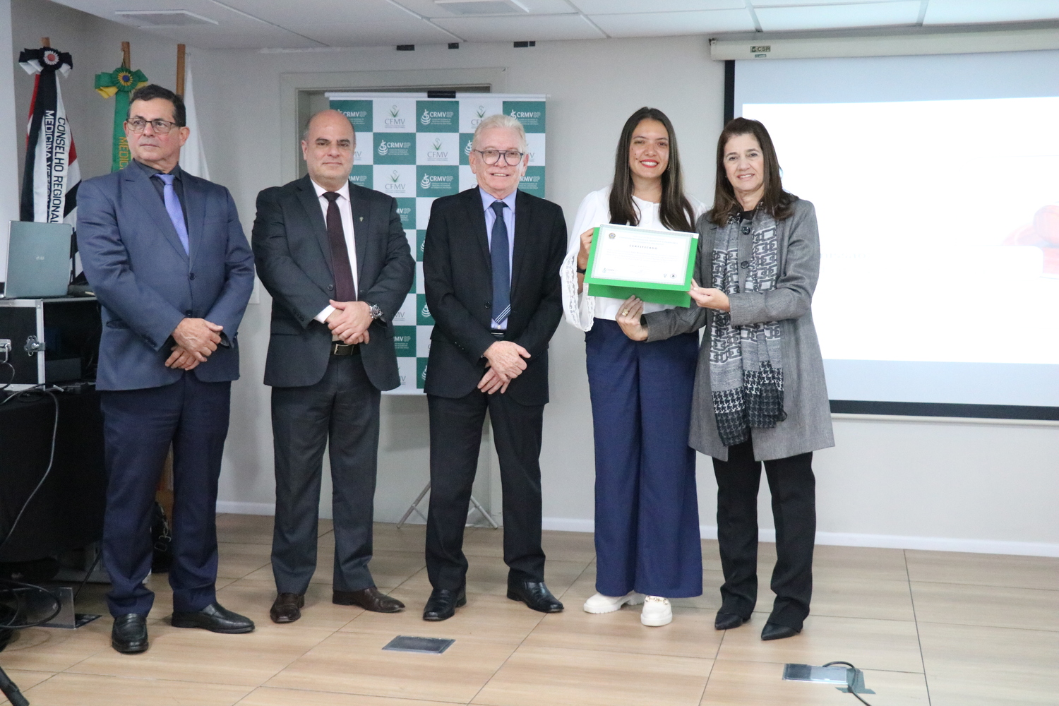 No palco, os membros da Diretoria Executiva do CRMV-SP posam ao lado de uma presidente de Comissão Técnica homenageada com certificado em reconhecimento ao trabalho desempenhado.