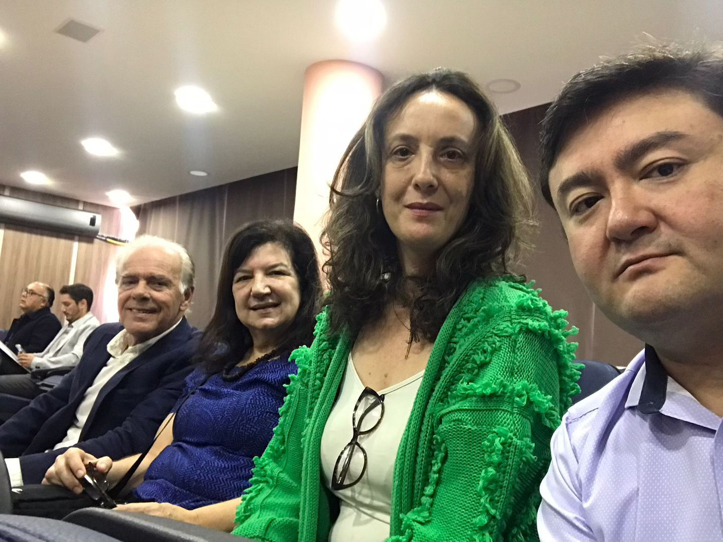 Dois homens e duas mulheres sentados em um auditório, pousando para foto.