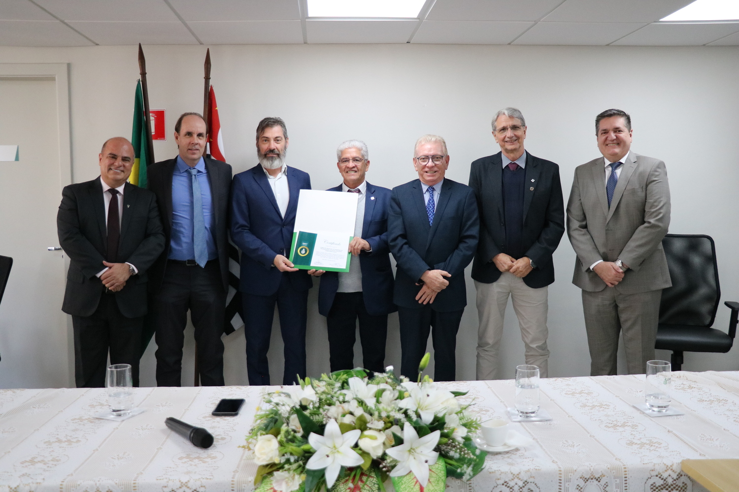 Sete homens, lado a lado, sendo dois membros da Diretoria Executiva do CRMV-SP, e os demais representantes da FMVZ-Unesp - Campus Botucatu, com o certificado recebido.