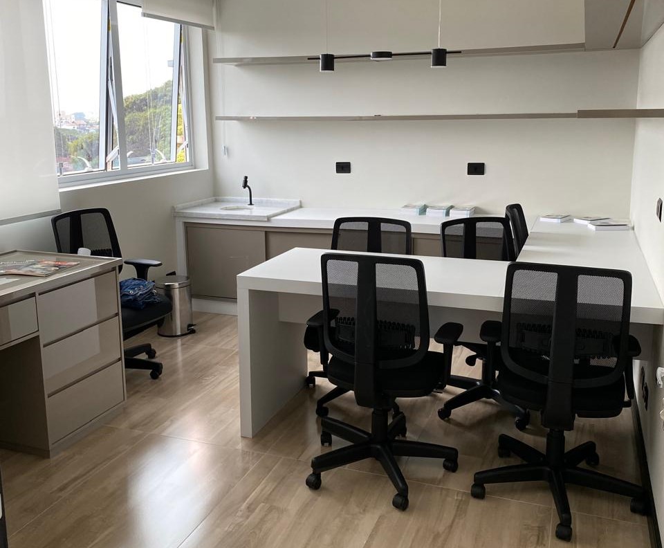 Sala de escritório com mesas em L, cadeiras giratórias e material de escritório em Taubaté.