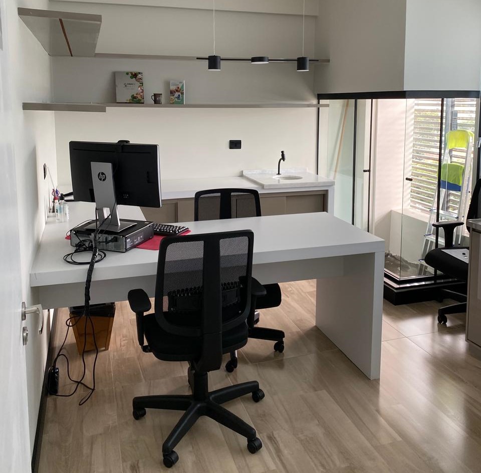 Sala de escritório com mesas, cadeiras giratórias, computador e material de escritório em Taubaté.