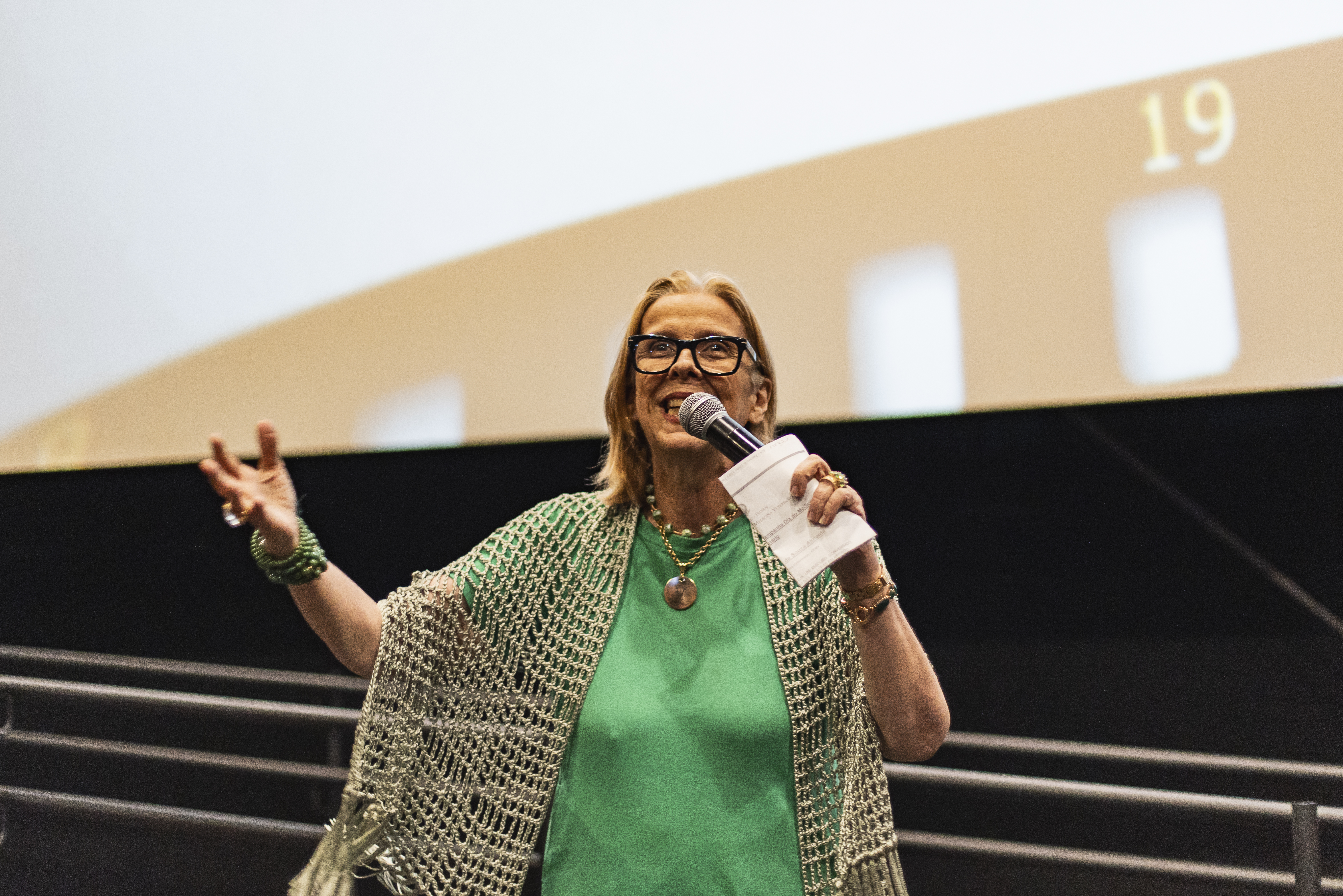 Mulher com microfone na mão discursando.