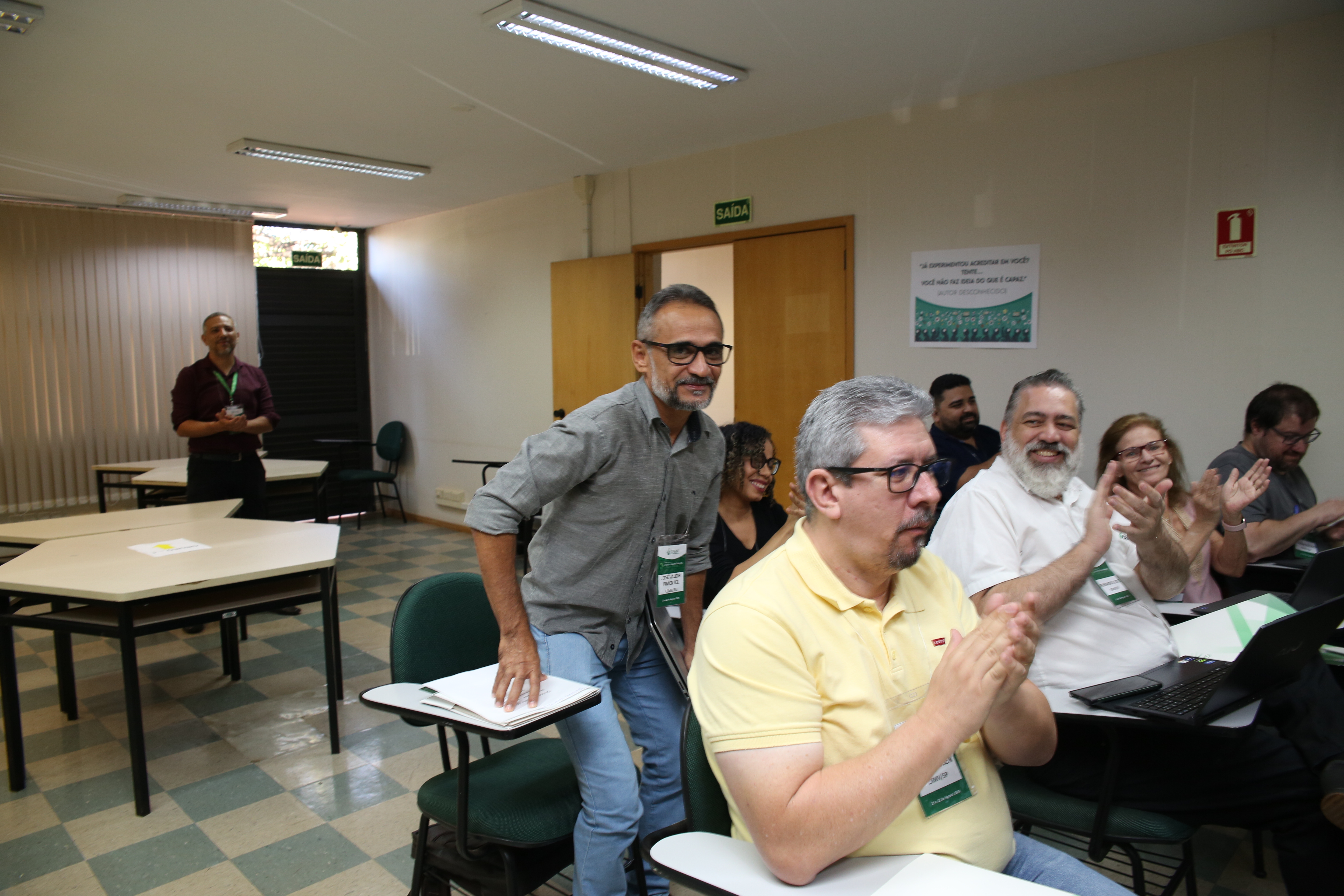 Fileira de pessoas sentadas durante o curso, sorrindo e aplaudindo.