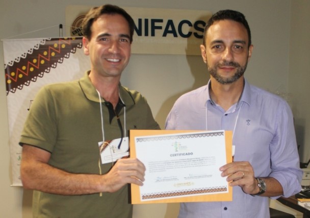 na foto, Rodrigo Mainardi sorri para foto junto de Cristiano moraes. os dois estão segurando um certificado