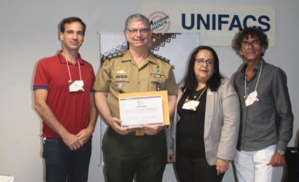 Na foto, Rodrigo Mainardi; o Coronel José Roberto Pinho; a organizadora do Simpósio e presidente da Comissão de Medicina Veterinária Legal do CRMV-BA, Lívia Peralva; e o ex-vice-presidente do CRMV-BA (2019-2022), Lúcio Leopoldo Aragão da Silva sorriem para foto.