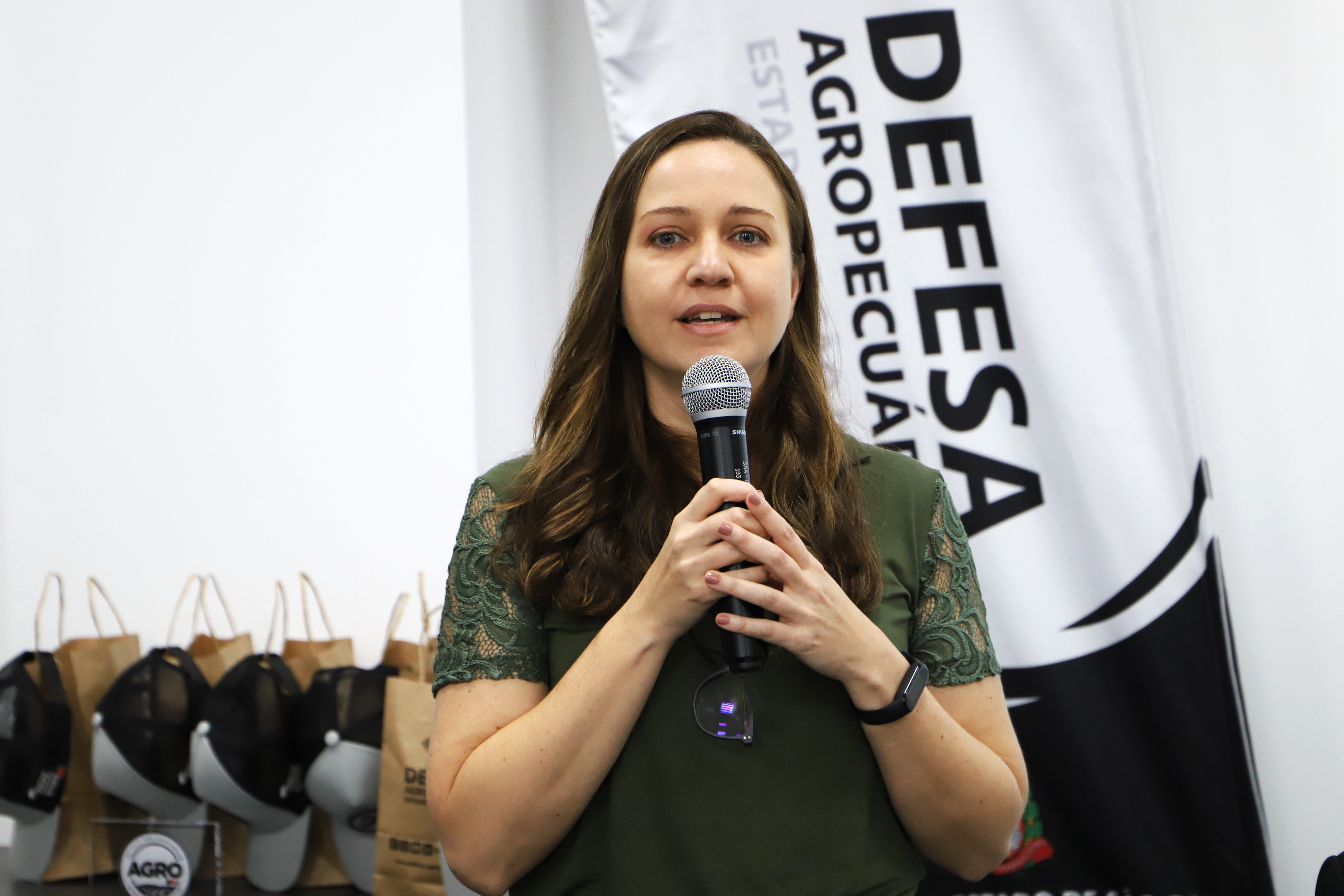 Mulher discursando segurando microfone com duas mãos.