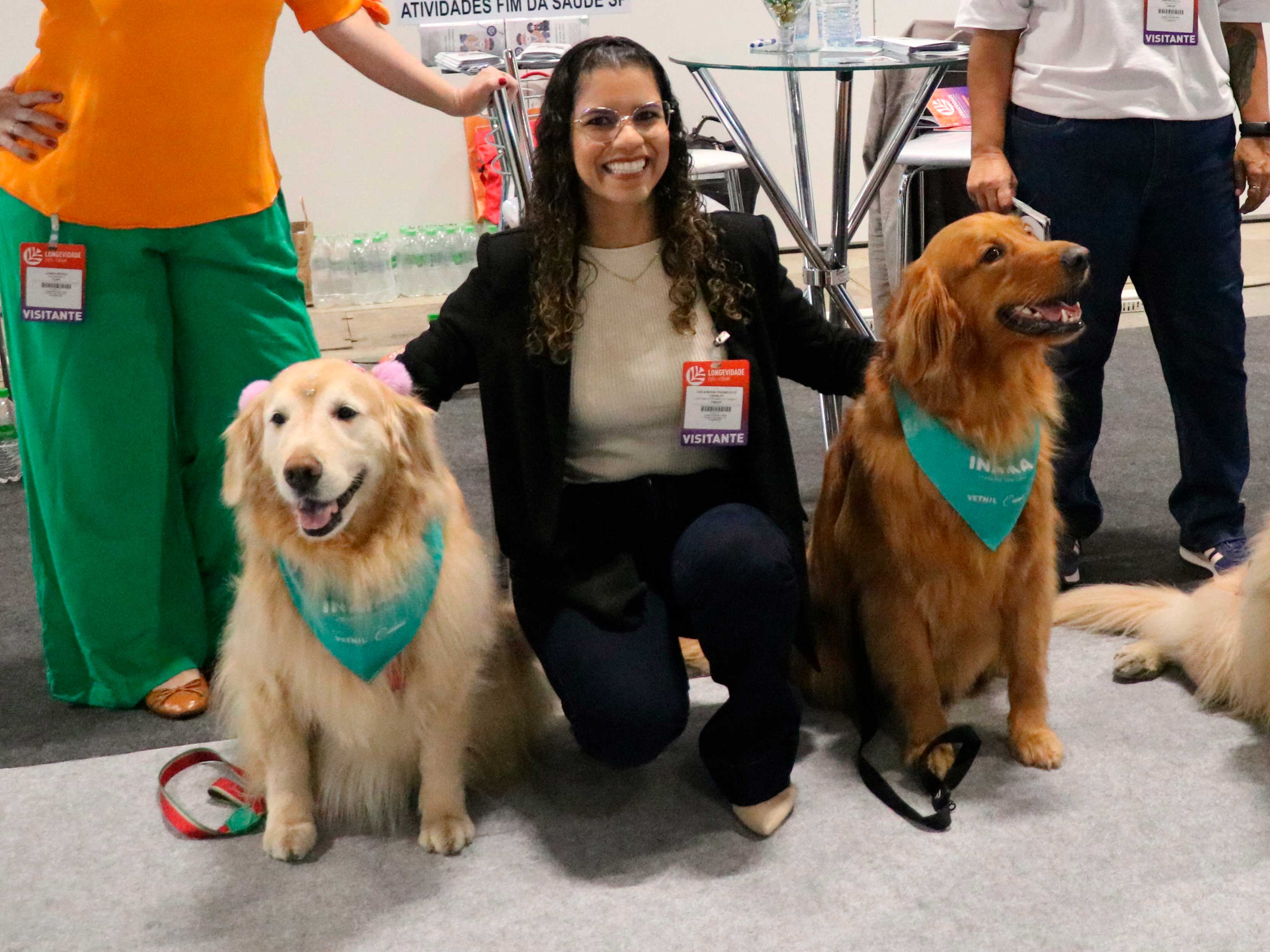 mulher abraçada com dois cães em evento