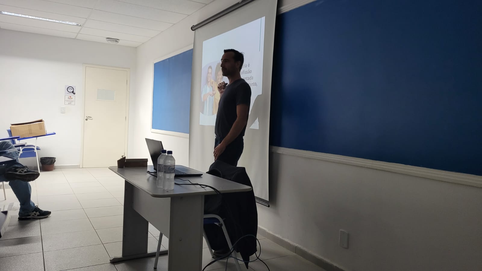 Rodrigo Mainardi palestra enquanto aponta para tela com slides.