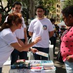 Pessoa apontando para imagens relacionadas a caravana da saúde enquanto outros observam.