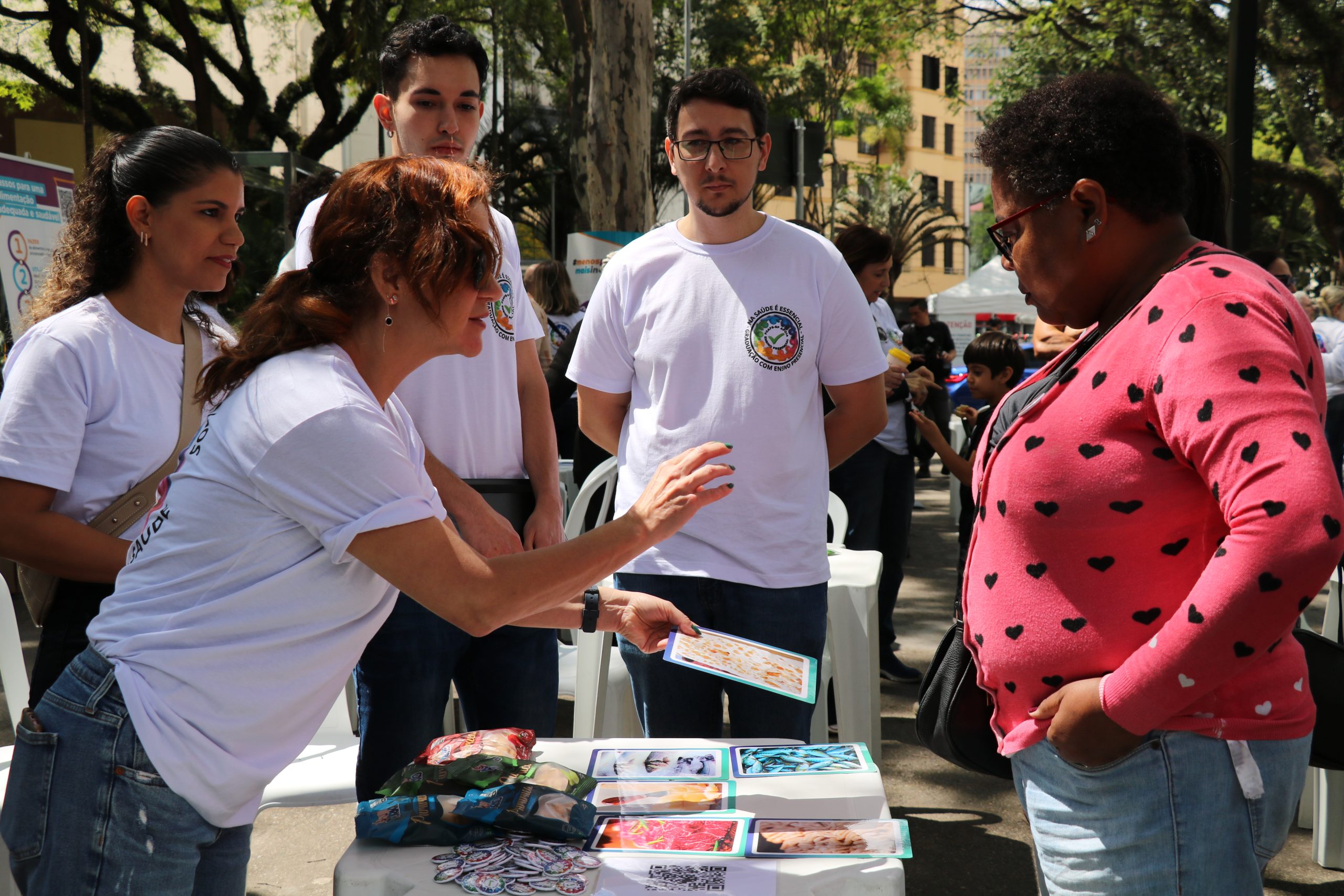 Pessoa apontando para imagens relacionadas a caravana da saúde enquanto outros observam.