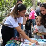 Pessoa apontando para imagens relacionadas a caravana da saúde enquanto outros observam.
