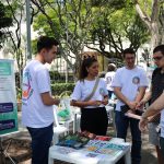 Pessoa falando sobre temas da caravana da saúde enquanto outros observam.