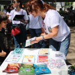 Pessoa apontando para imagens relacionadas a caravana da saúde enquanto criança observa.
