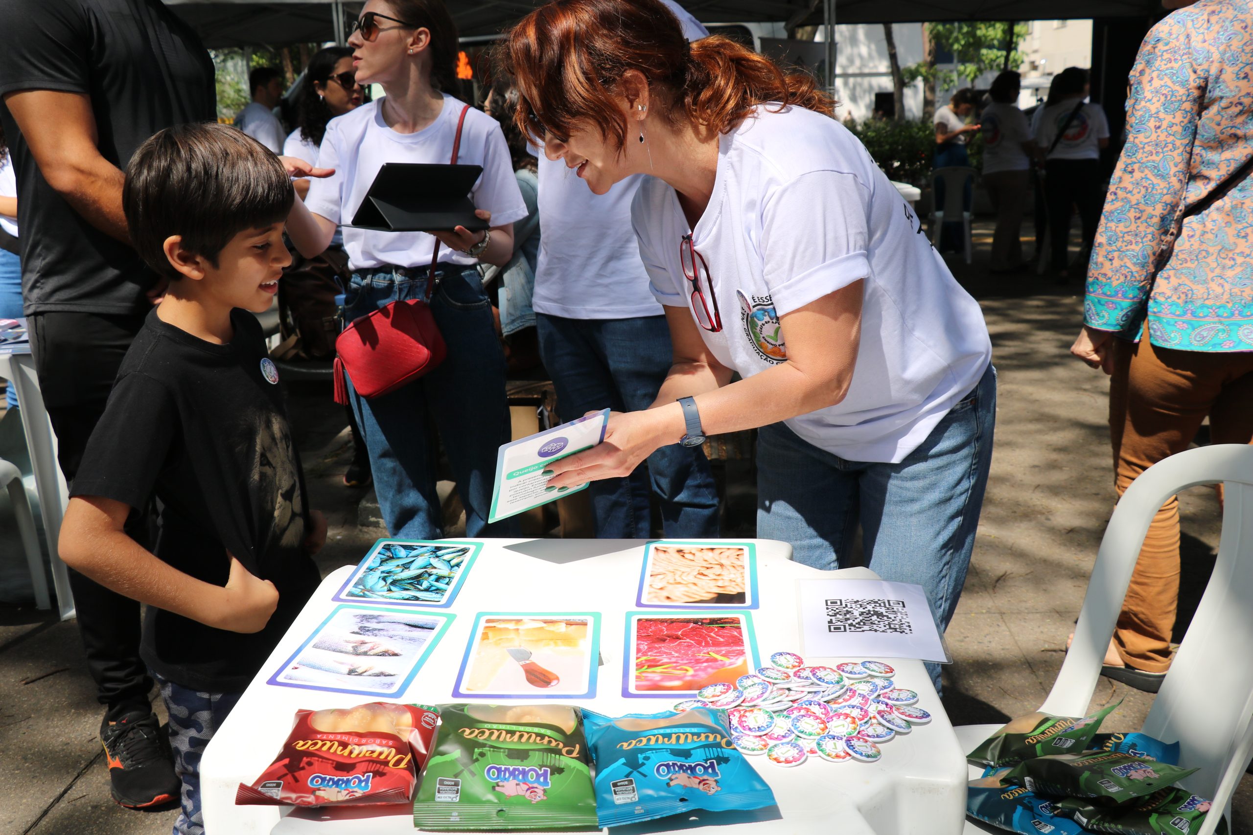 Pessoa apontando para imagens relacionadas a caravana da saúde enquanto criança observa.