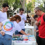 Pessoa apontando para imagens relacionadas a caravana da saúde enquanto outros observam.