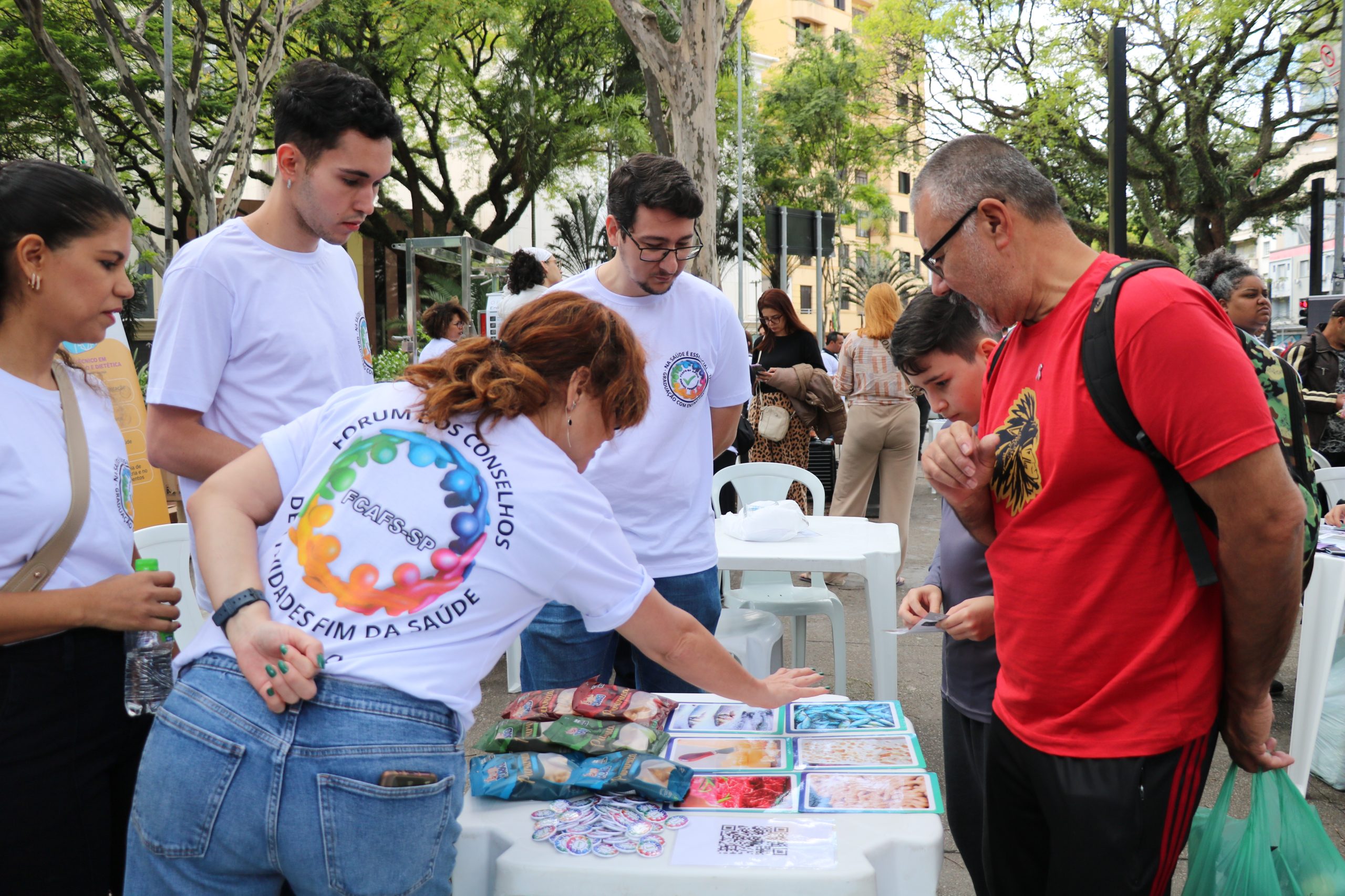 Pessoa apontando para imagens relacionadas a caravana da saúde enquanto outros observam.