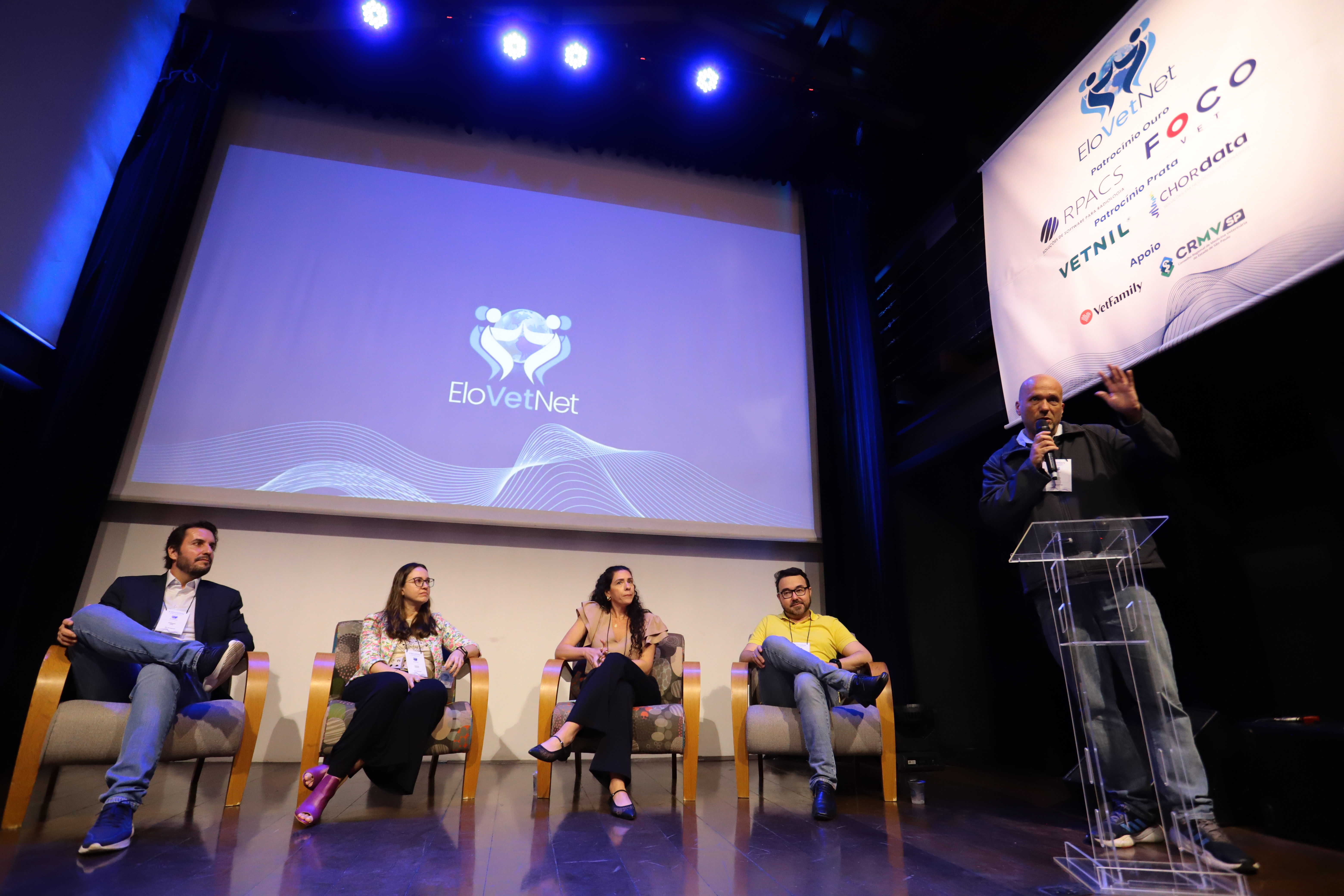 Pessoas palestrando sentadas em palco