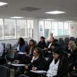 Pessoas em auditório prestando atenção.