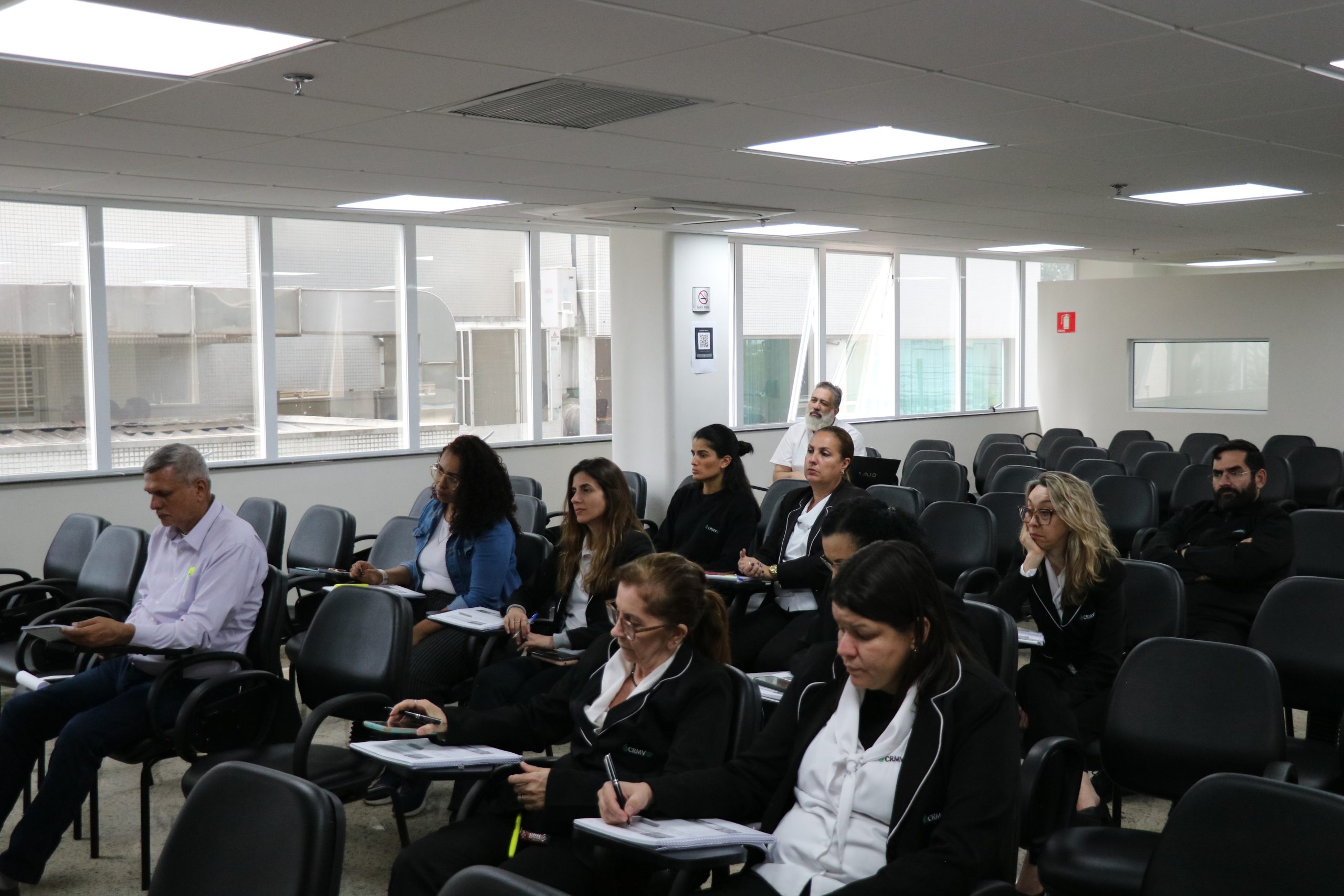 Pessoas em auditório prestando atenção.