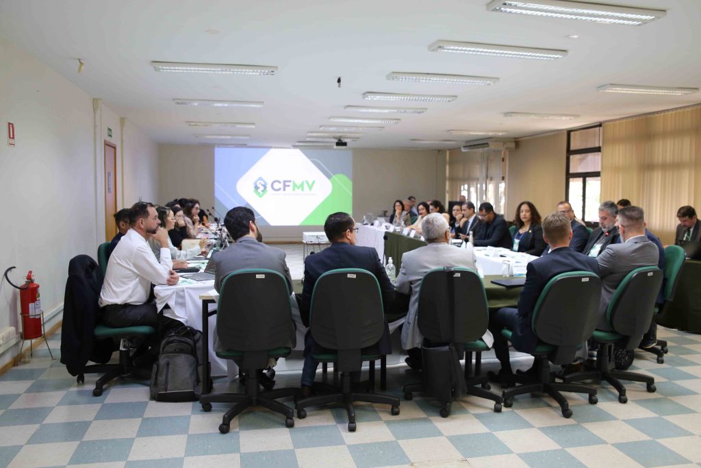 Pessoas de costas para a câmera sentadas em reunião.