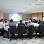 Pessoas de costas para a câmera sentadas em reunião.