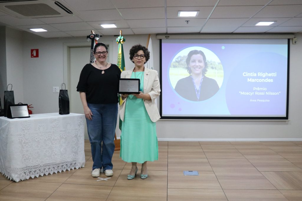 A secretária-geral do CRMV-SP entrega a placa à premiada na categoria Pesquisa.