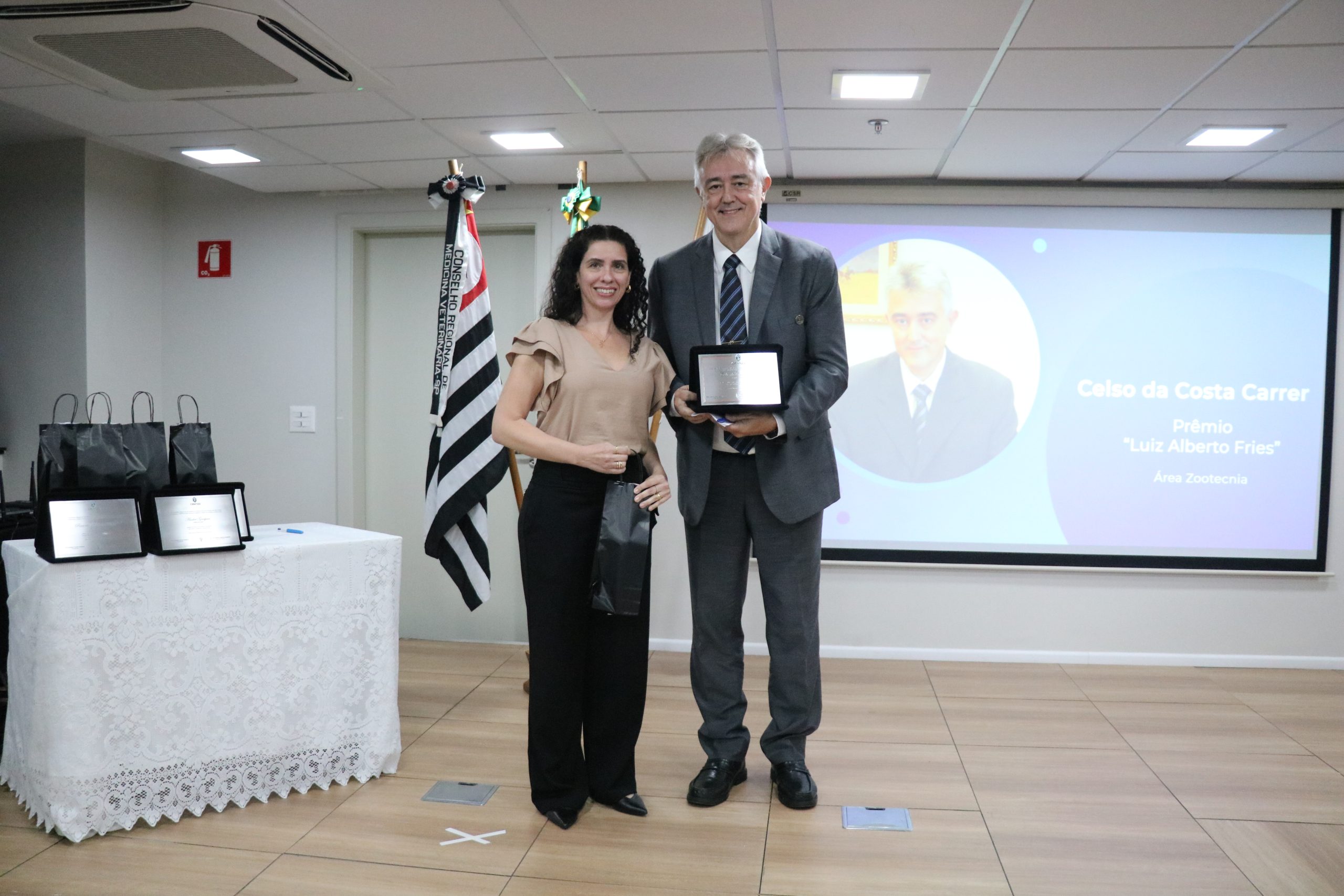 A vice-presidente do CRMV-SP entrega a placa ao premiado na categoria Zootecnia.