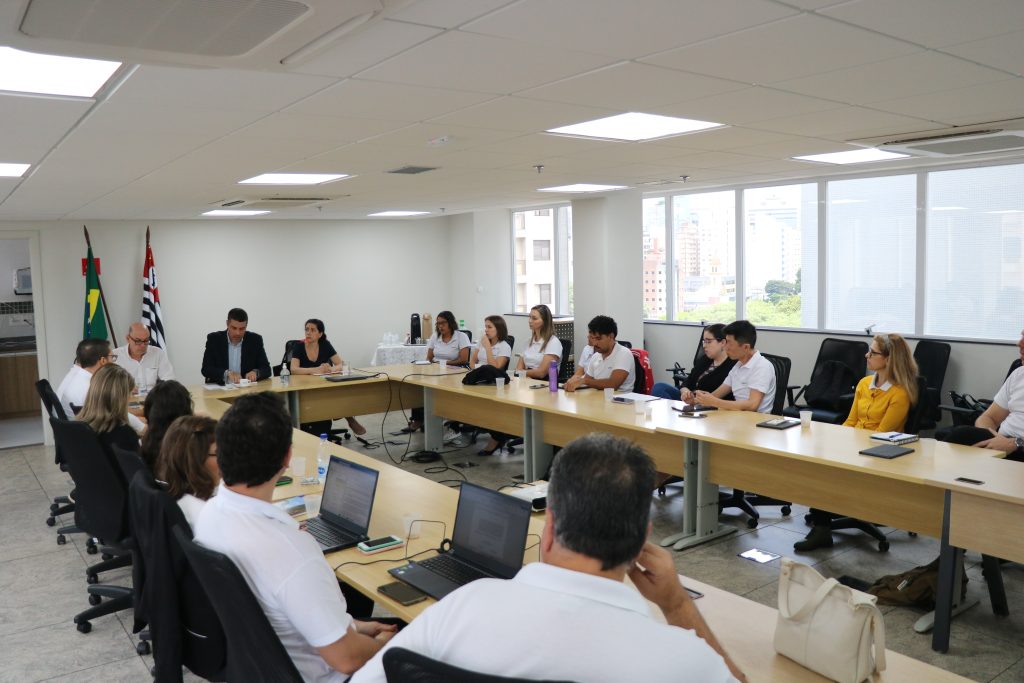 Pessoas sentadas reunidas em volta de uma mesa discutindo plano anual de fiscalização 2025.