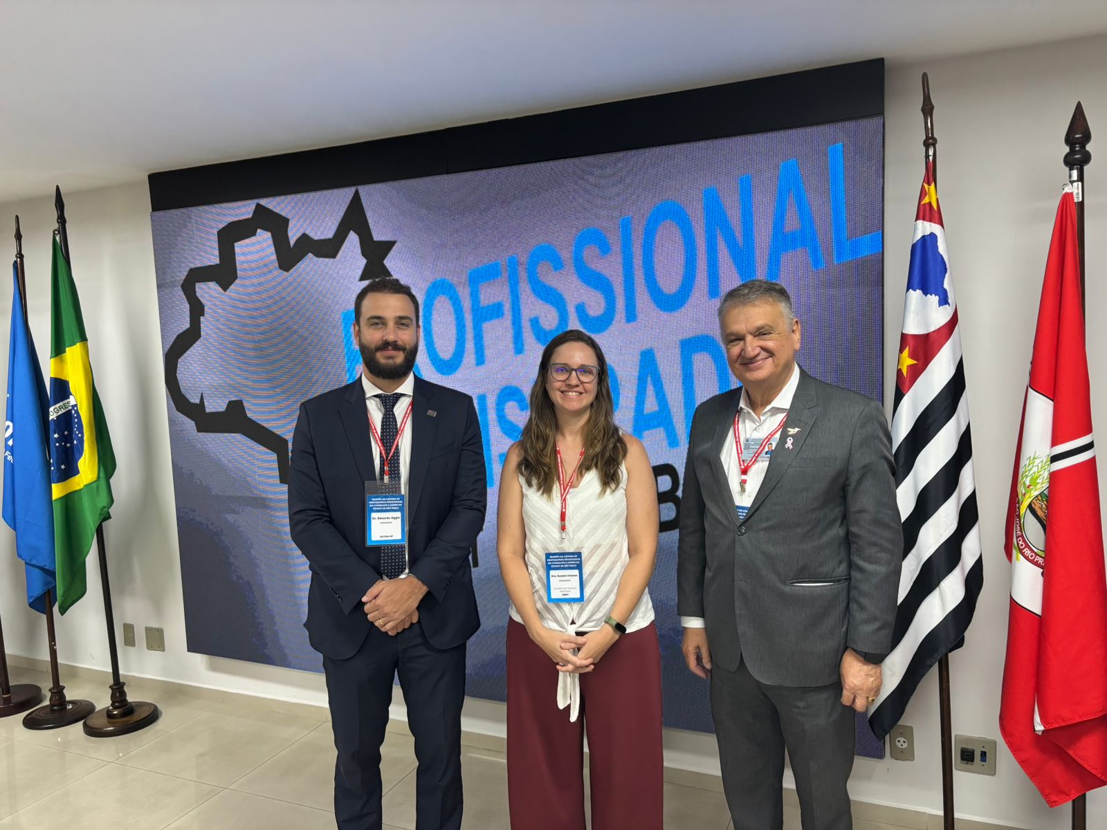 homens de terno posando para foto com mulher de branco. Essa é a presidente Daniela.