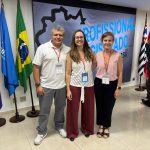 homem de camiseta branca posando para foto com 2 mulheres uma de branco e outra de rosa