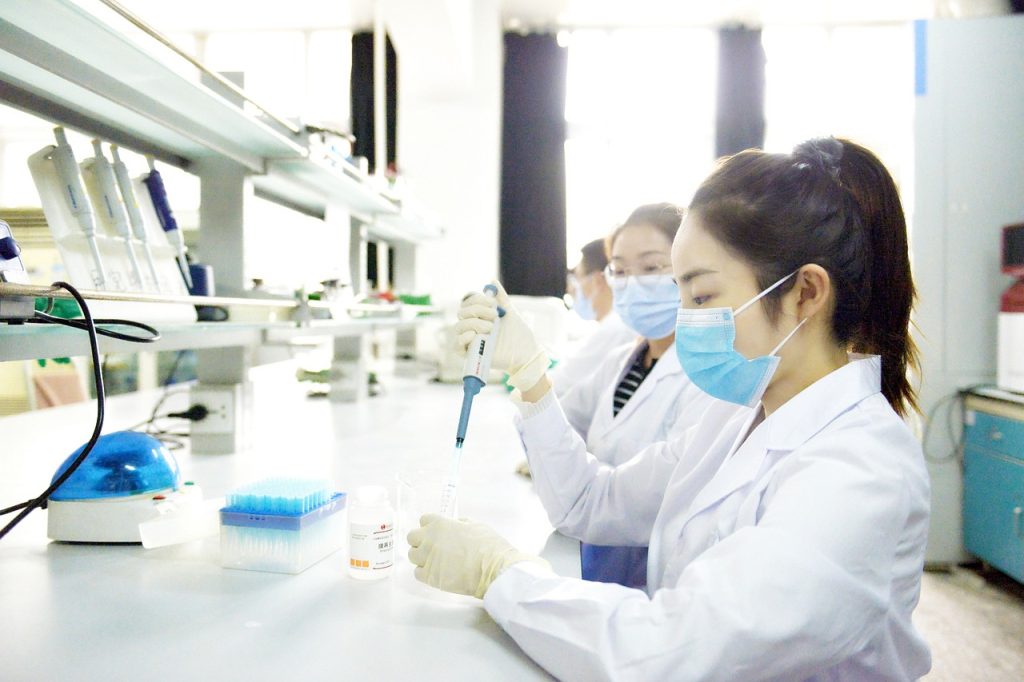 jovens mulheres de jaleco branco máscara trabalhando em um laboratório.