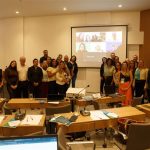 Pessoas reunidas frente a uma tela posando para foto.