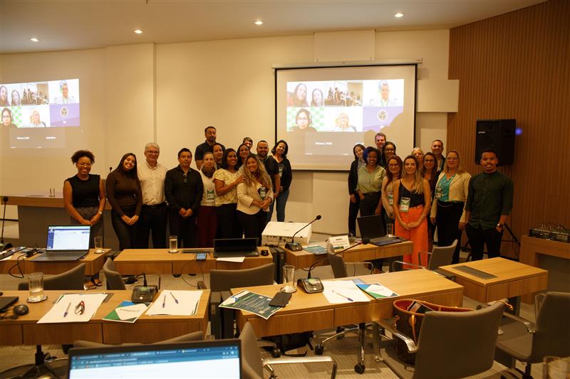 Pessoas reunidas frente a uma tela posando para foto.