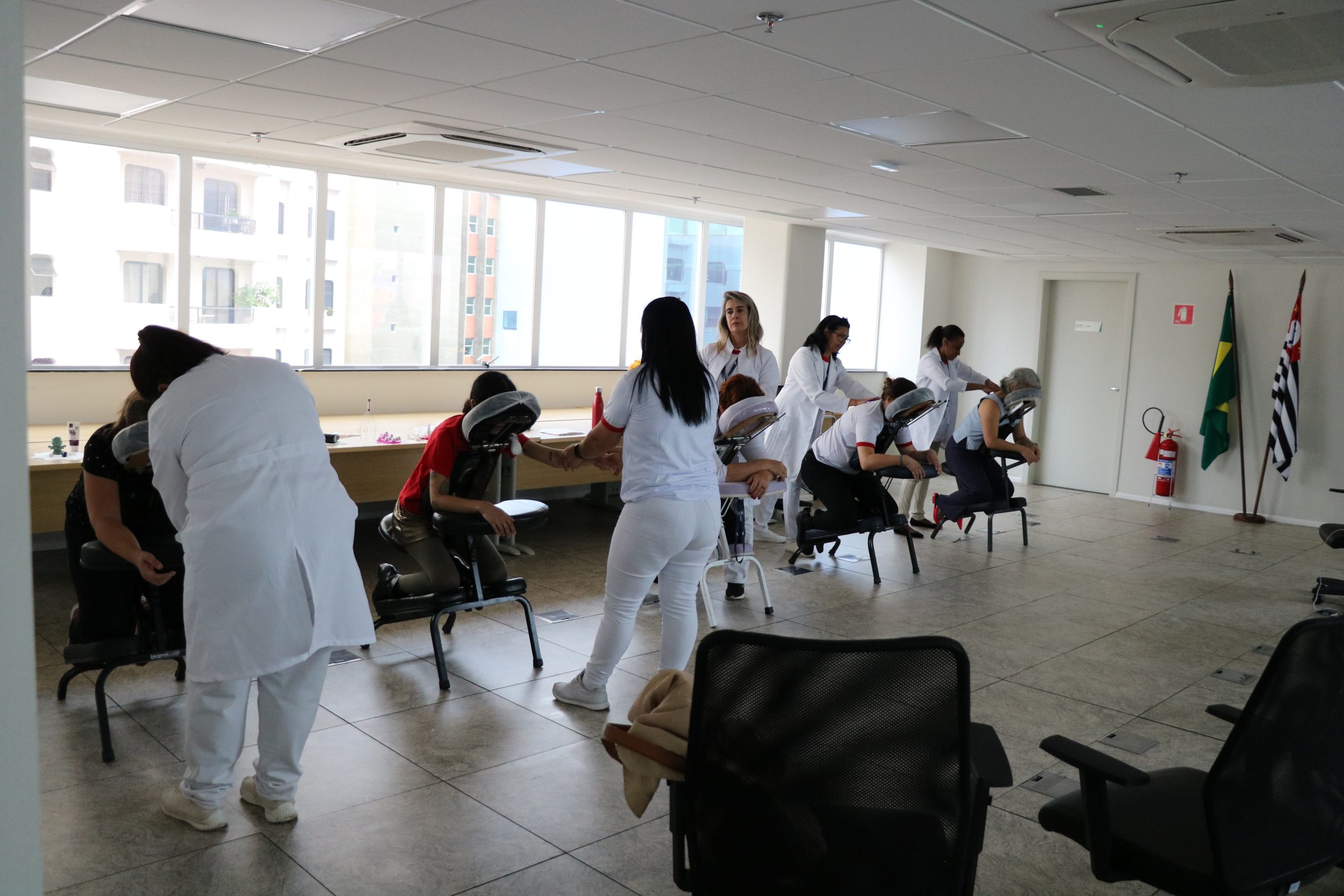 Na foto há algumas mulheres encostadas recebendo uma sessão de massagem.