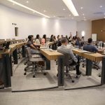 Pessoas sentadas em bancada assistindo a apresentação.