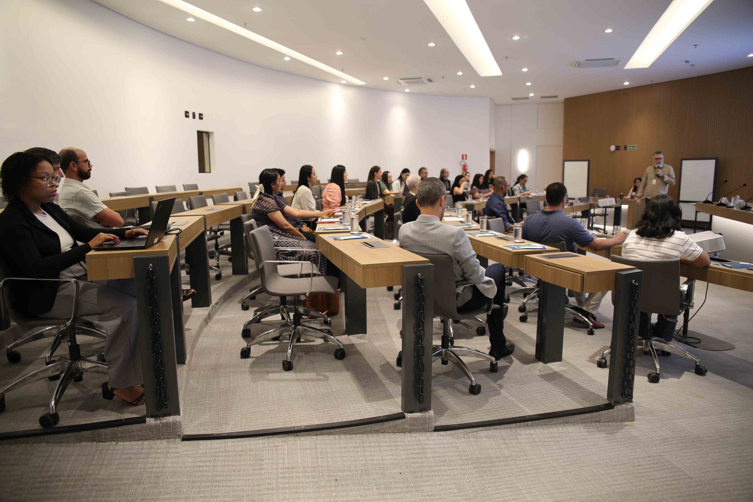 Pessoas sentadas em bancada assistindo a apresentação.