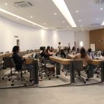 Pessoas sentadas na bancada assistindo a apresentação.