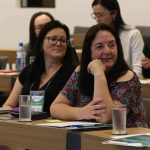 Em destaque: mulher branca de fios lisos pretos e médios, é a coordenadora de atendimento e registros, Geni da Silva.