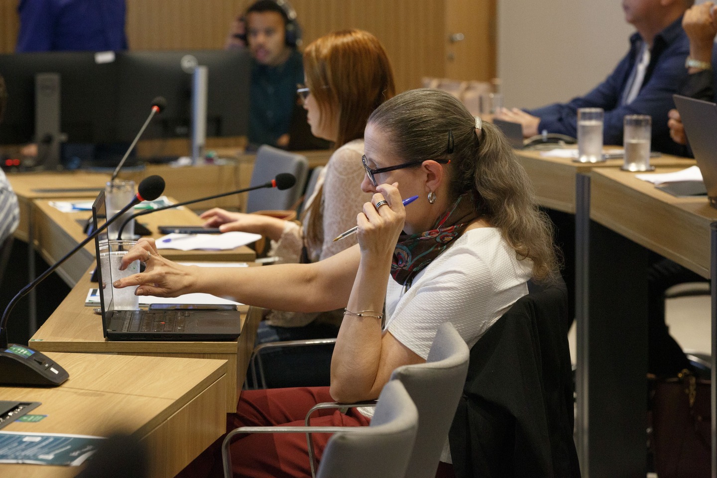 Mulher de cabelos loires de óculos sentada, frente ao computador.