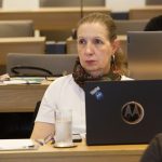 Mulher de cabelos loiros, camisa branca e cachecol.