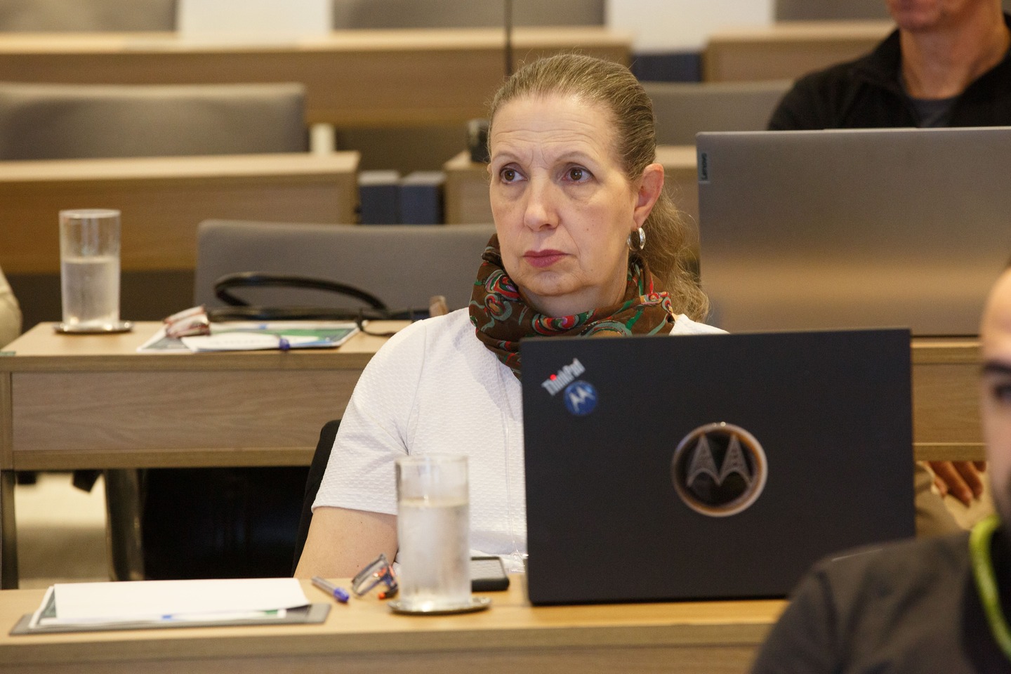 Mulher de cabelos loiros, camisa branca e cachecol.