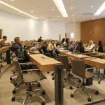 Pessoas sentadas frente a apresentação.