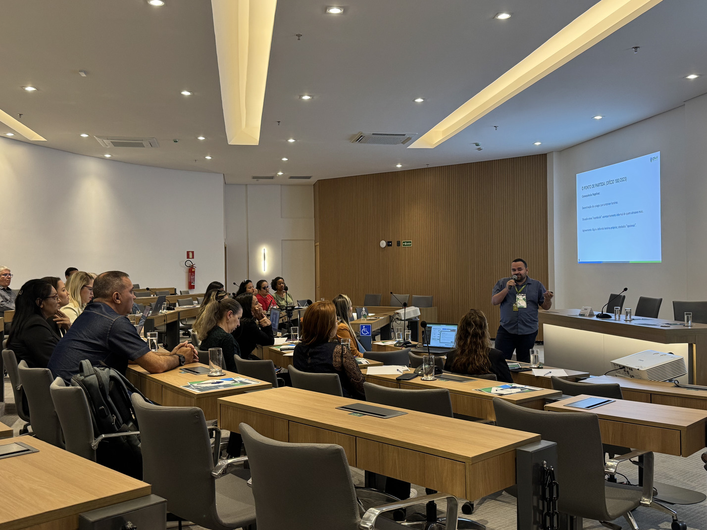Pessoas sentadas olhando apresentação.