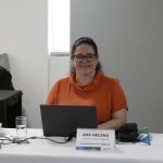 Uma mulher de pele branca, cabelo preto, camiseta laranja e utilizando óculos. Essa é a secretária geral do CRMV-SP Ana Helena Pagotto.