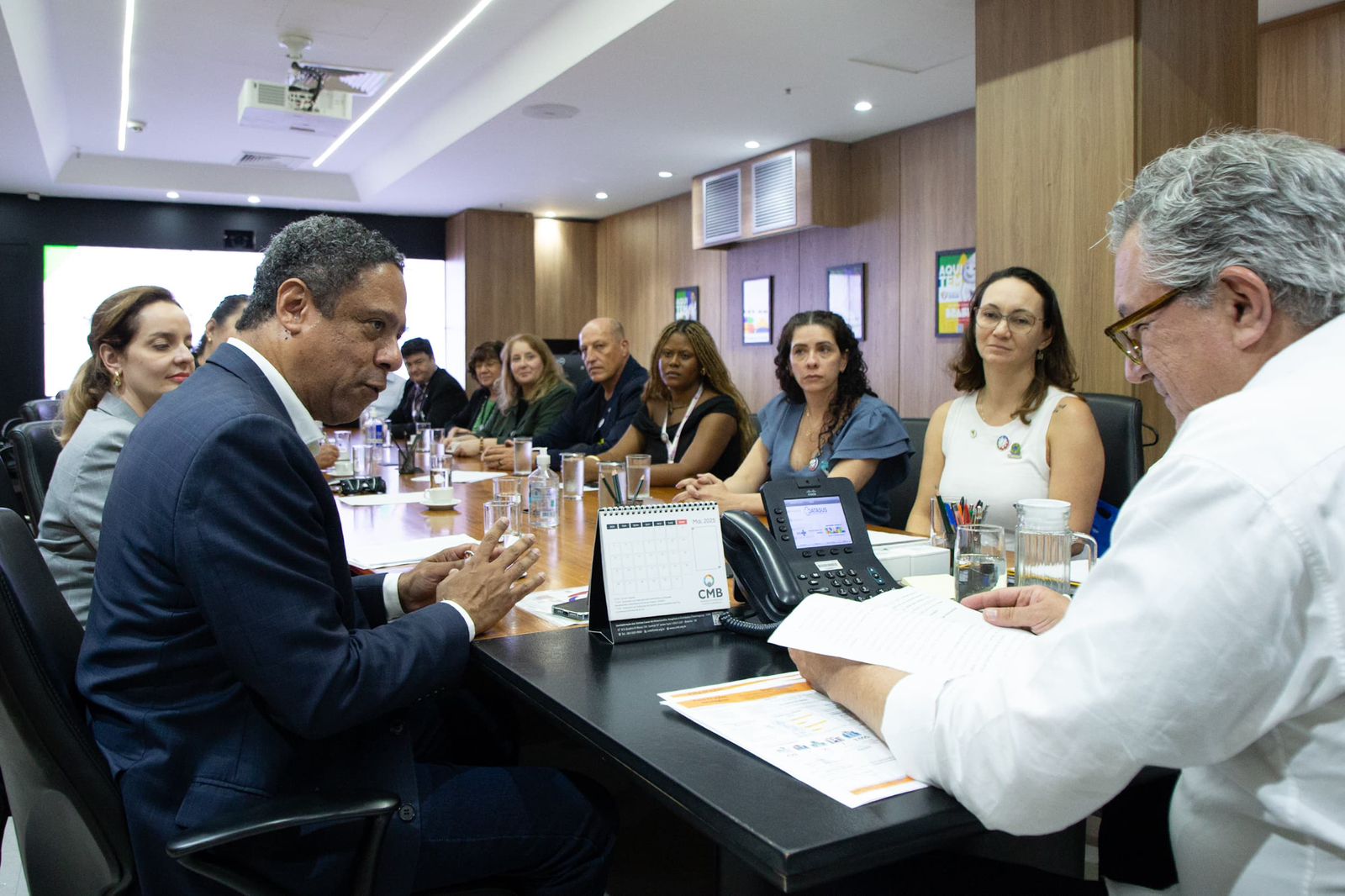 Pessoas sentadas a mesa discutindo pautas.