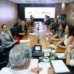 Pessoas sentadas a mesa em reunião.