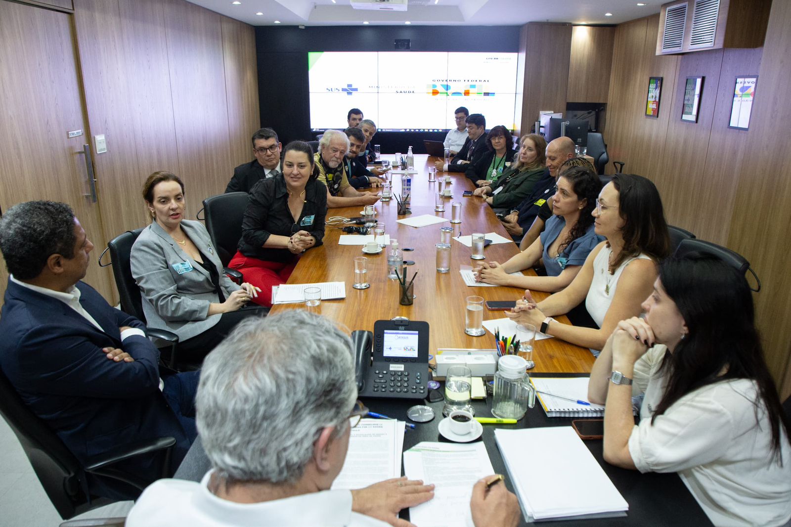 Pessoas sentadas a mesa em reunião.