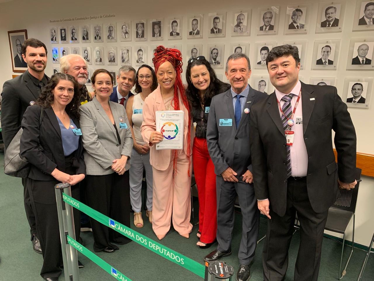 Pessoas em pé, reunidas para foto com deputada federal, Daiana Santos.